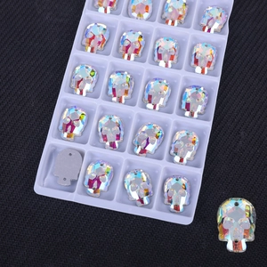 Macro shot of skull-shaped AB crystal glass rhinestones with dual-hole design in a tray