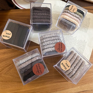 Close-up of premium satin scrunchies in stylish neutral colors inside a clear gift box