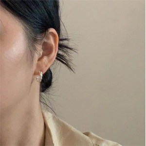 Close-up of a minimalist silver twisted rope hoop earring on a model's ear