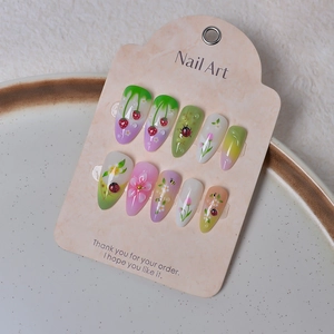 Detail of almond-shaped nails featuring 3D strawberry, flower, and ladybug art