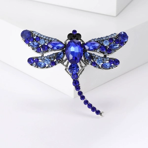 Elegant dragonfly brooch with blue crystals on white background for creative fashion style