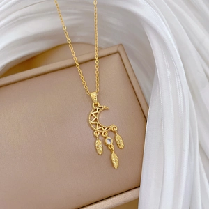 Macro detail of gold moon pendant with crystal and feather charms on jewelry box
