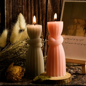 Close-up of lit knotted pillar candles with ribbed texture on vintage wood background