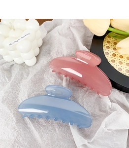 Detail of semi-circular matte hair claws in dusty blue and rose pink on white background