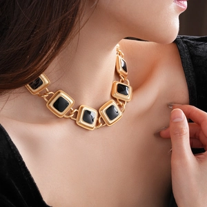 Close-up of vintage gold square link necklace with black enamel inlay on model's neck