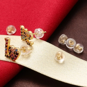Detailed macro view of gold heart stud earrings with rainbow stones and earring backs