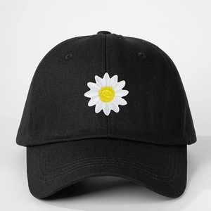 Close-up of daisy embroidery and stitching on a black cotton canvas baseball cap