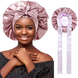 Close-up of pink satin sleep bonnet featuring a bow knot and long ribbon ties