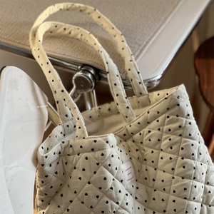 Détail du sac cabas matelassé en velours avec motif cœurs noirs et étiquette en tissu
