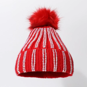 Detail of red knitted beanie featuring vertical rhinestones and a fluffy faux fur pompom