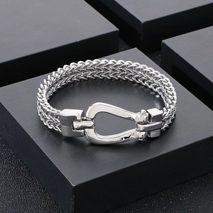 Polished stainless steel braided chain bracelet with U-shaped horseshoe buckle on display