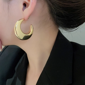 Close-up of a model wearing high-polished chunky gold C-shaped hoop earrings