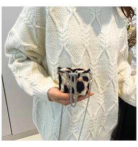 Close-up of mini leopard print chain bag held in hand showing compact size and texture