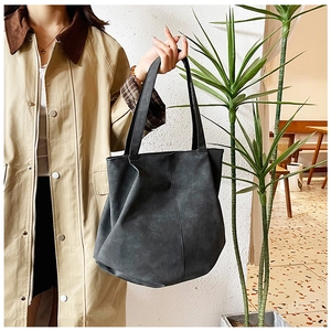 Close-up of black leather tote bag with vertical stitching and long shoulder straps