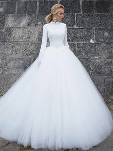 Detail of high-neck lace bodice and voluminous tiered tulle skirt on a white wedding gown