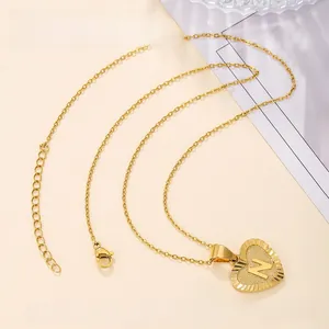 Detail view of a gold heart pendant with engraved letter N and radial texture pattern
