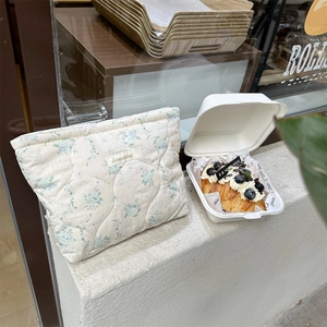 Close-up of quilted floral cotton makeup bag with blue flowers on a rustic windowsill