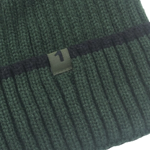 Detail of dark green ribbed knit beanie showing textured fabric and numeric number 1 patch