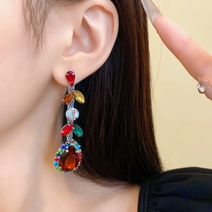 Close-up of elegant long tassel earrings with colorful rhinestones and leaf-shaped details