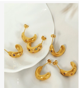 Detail of gold crescent earrings featuring vibrant multi-colored inlaid zircon stones