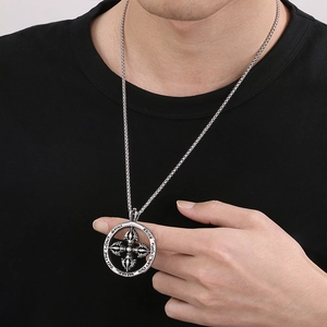 Detailed close-up of a silver stainless steel vajra pendant necklace on a black shirt