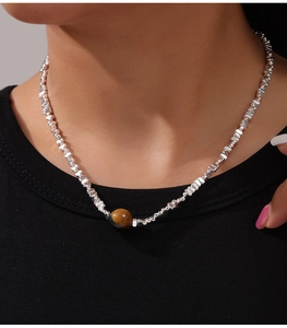 Detailed close-up of tiger eye pendant and irregular silver metal beads on a necklace