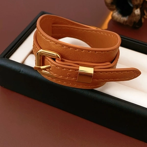 Close-up of caramel faux leather wrap bracelet with gold buckle in a black gift box