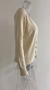 Detail van beige gebreid vest met V-hals, geribbelde manchetten en knoopsluiting