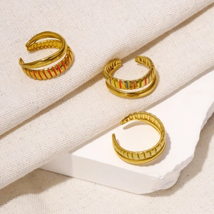 Three-piece gold adjustable ring set with colorful enamel stripes on a stone background