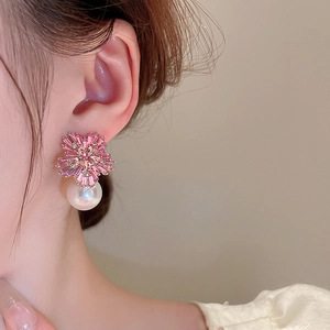 Detail view of crystal flower earrings with white pearl drop on a model's ear