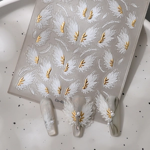 3D Angel Wings nail art stickers with white feathers and gold accents on a sheet