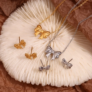 Detailed view of 18K gold and silver bow pendant necklaces and matching stud earrings