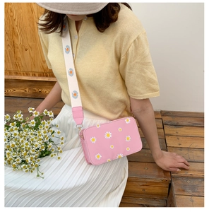 Close-up of pink crossbody bag with daisy prints and matching wide shoulder strap