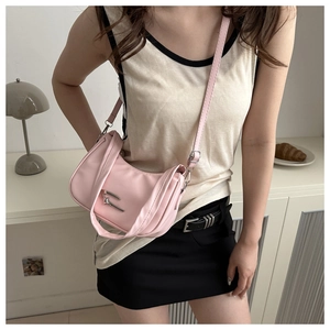 Pink crescent underarm bag with silver hardware on a model in a minimalist setting
