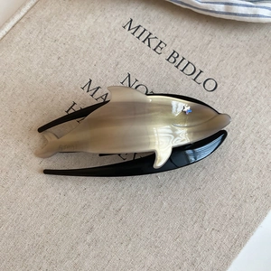 Detail of acrylic whale hair claw clip with marble texture and star accent decoration