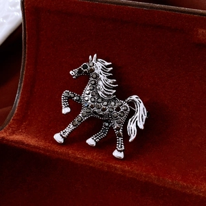 Macro view of a galloping horse brooch with grey rhinestones on red velvet
