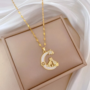 Detailed shot of golden moon and cat pendant necklace with zircon on a beige jewelry box