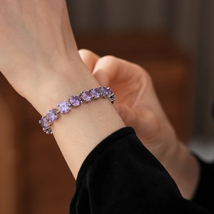 Macro shot of purple round-cut zircon bracelet with silver claw setting on woman's wrist