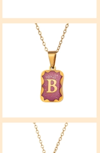 Macro detail of gold-plated rectangle pendant with purple enamel and letter B engraving