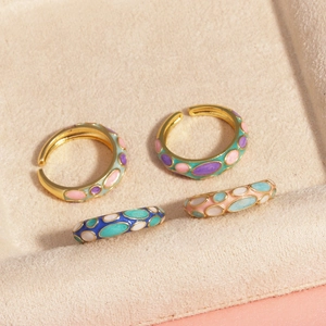 Détail de bagues en émail coloré présentées sur un plateau à bijoux en velours beige