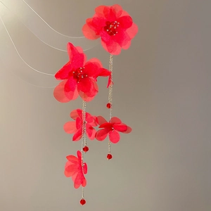 Detail showing red fabric flower petals and long silver chain tassels with red beads