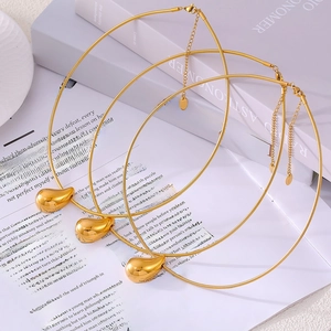 Gold-plated stainless steel teardrop pendant choker necklace displayed on a white book