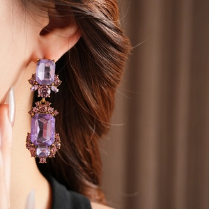 Close-up of vintage geometric square gold earrings with purple crystal stones on a model