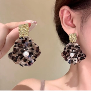 Detail of leopard print flower earrings with gold metal studs and white pearl accents