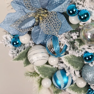 Detail of blue silk flowers and snowy pine needles on a luxury Christmas wreath