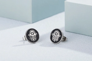 Detail of silver and black stud earrings with creative hand palm design on geometric background