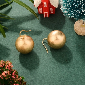 Boucles d'oreilles boules dorées avec décorations de Noël sur une surface verte