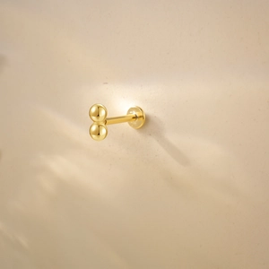 Macro shot of gold silver cartilage earring with double ball design and smooth finish
