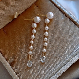 Détail de boucles d'oreilles pendantes en perles avec gouttes dans un écrin velours