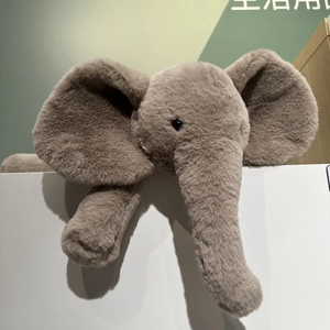 Detail of cute grey plush elephant toy lying on a shelf with long trunk and soft fur